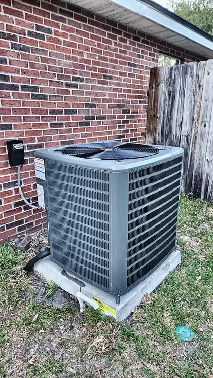 AC condenser on a concrete pad against a brick home exterior, Jacksonville FL