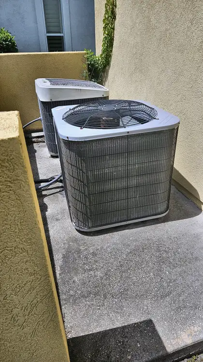 Two AC condenser units on a shared pad at a stucco property, Northeast Florida