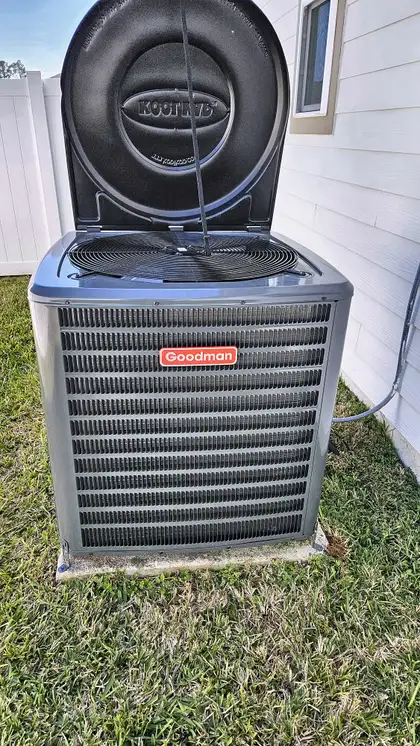 New Goodman AC condenser with protective fan cover raised during installation, Northeast Florida