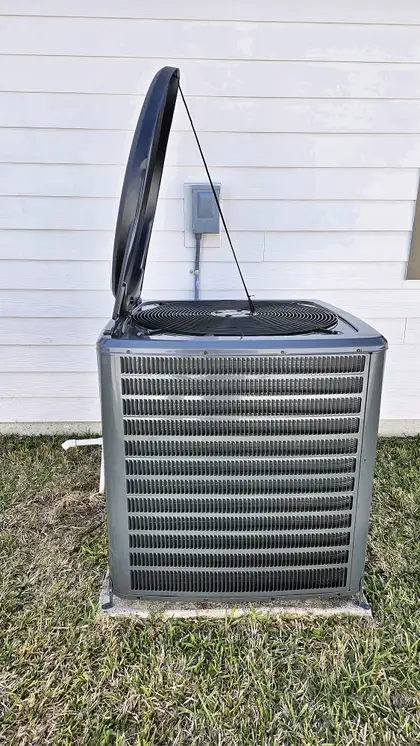 Side view of a newly installed AC condenser with top cover open, Jacksonville area home